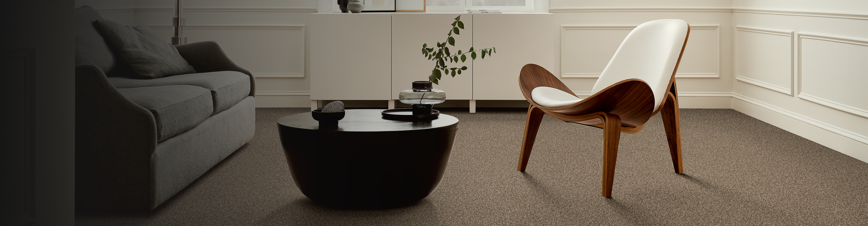 beige carpet in modern living room with black coffee table, abstract art and white modern chair