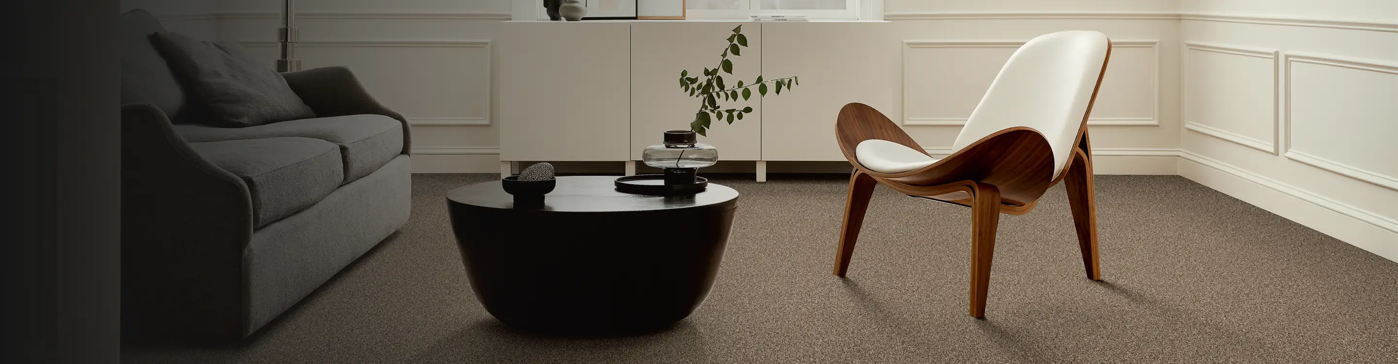 beige carpet in modern living room with black coffee table, abstract art and white modern chair